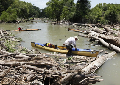 Rowing canoe crossing a log jam in Texas Water Safari